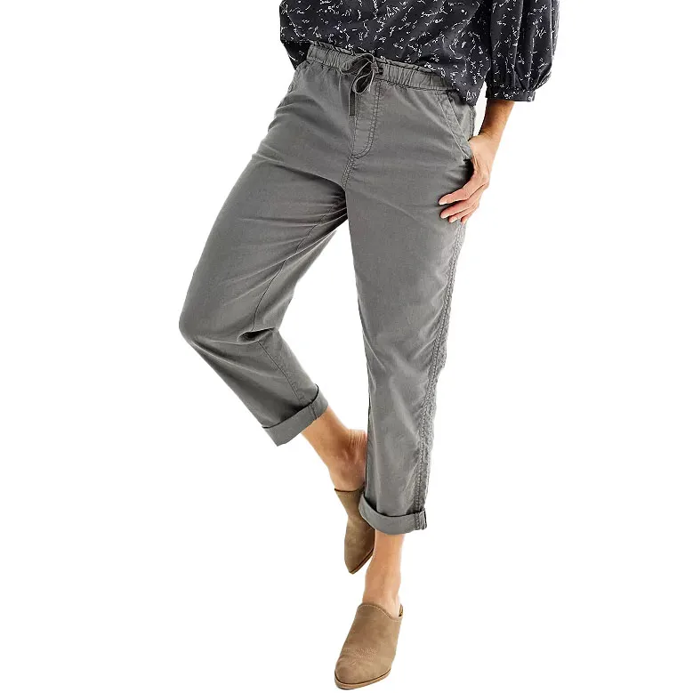 Gray drawstring pants with rolled cuffs paired with a dark patterned top and tan slip-on shoes.