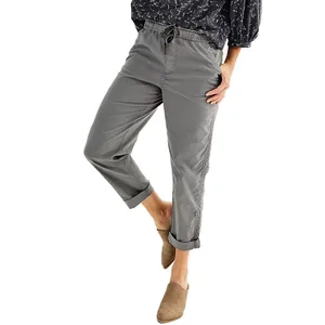 Gray drawstring pants with rolled cuffs paired with a dark patterned top and tan slip-on shoes.