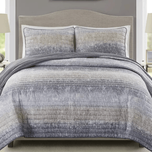 The 3pc Madison Park Queen Quilt Set includes a quilt and two shams in a gradient pattern with gray tones and subtle texture. It features a contemporary style with stitched details for a modern bedroom look.