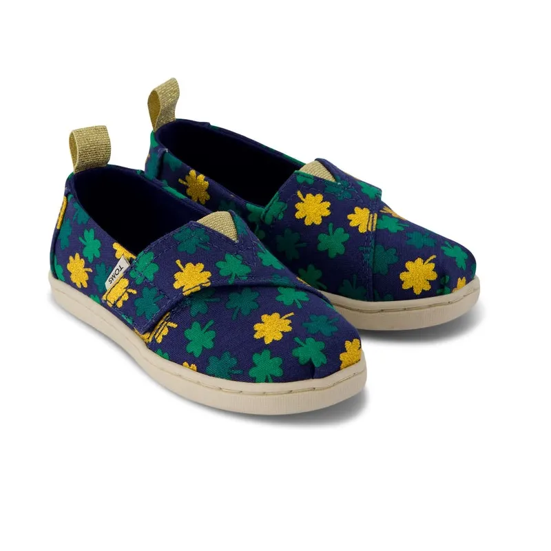 TOMS Alpargata Toddler Shoes feature a navy canvas with green and yellow shamrock designs, elastic gore for easy on and off, and a woven heel tab. They come with a durable rubber outsole for comfort and traction.