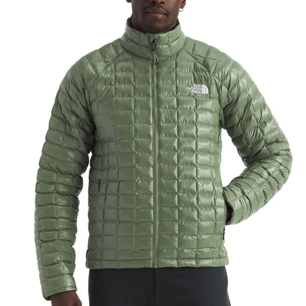 A green, quilted jacket from The North Face featuring a front zipper and two zippered pockets, designed for warmth and outdoor use.