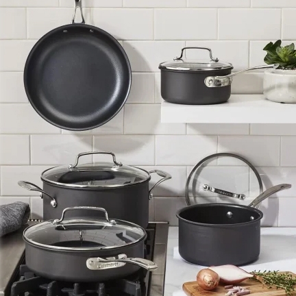 Cookware set includes frying pan, stockpots with lids, and a saucepan with lid, all in a sleek, dark finish.