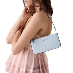 A person is holding a light blue Kate Spade New York shoulder bag. The person is wearing a pink, sheer, ruffled dress.