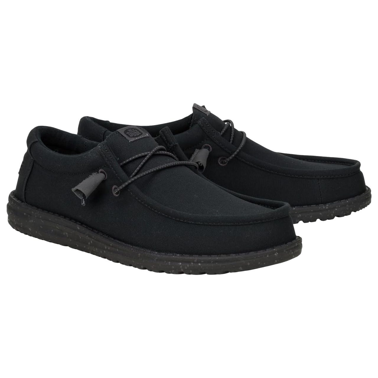 A pair of black, casual slip-on shoes with a moccasin-style design and lace detail. They have a low-profile sole with a speckled pattern.
