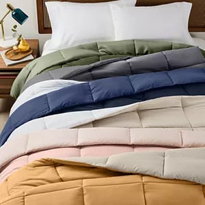 Arch Studio Reversible Comforter features a quilted design in multiple colors, including green, gray, navy, white, pink, and mustard. It's versatile for seasonal changes with a soft, cozy feel.