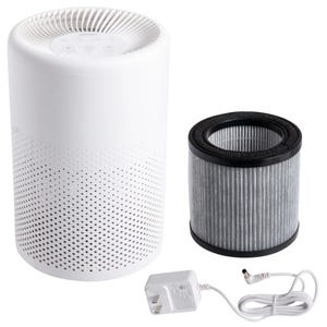 White cylindrical tabletop air purifier with perforated design, shown with a cylindrical replaceable filter and a white power adapter.