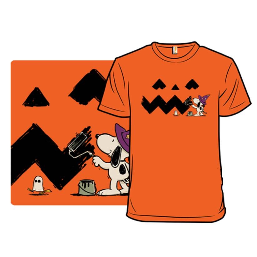 An orange T-shirt with a Halloween-themed graphic featuring a cartoon dog dressed as a ghost, surrounded by pumpkins and a small character in a witch hat.