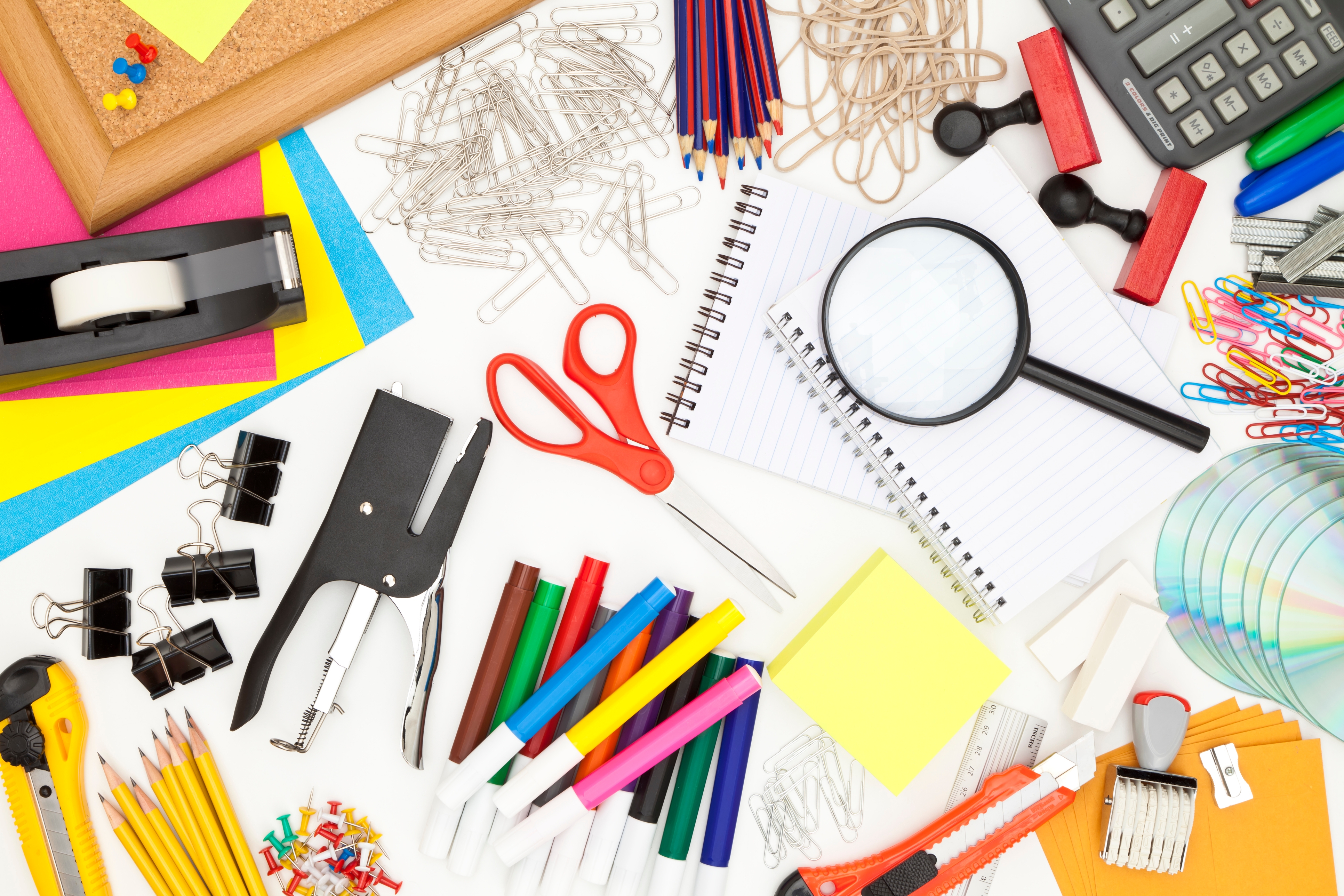 A variety of colorful office supplies including scissors, pens, paper clips, a magnifying glass, calculator, sticky notes, and a stapler.
