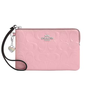 A pink Coach wristlet with embossed logo pattern, equipped with a zipper closure and a heart charm attached to the strap.