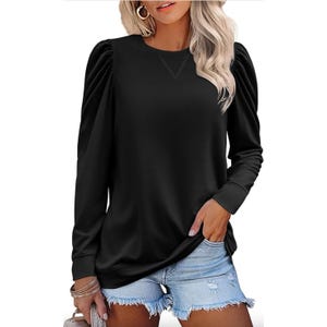 Black long-sleeve top with puffed shoulder details, paired with light denim shorts.