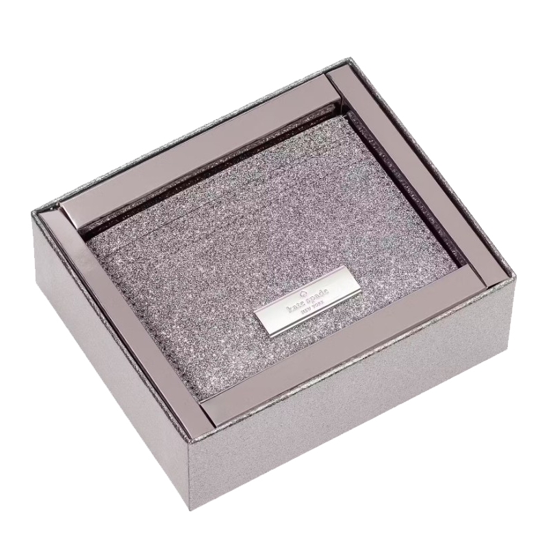 A glittery metallic box set containing a cardholder and keychain from Kate Spade New York, featuring a silver-tone logo plate on the cardholder.