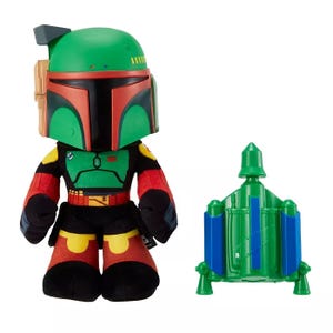 Stylized plush toy of a character in green and red armor with matching plastic backpack accessory.