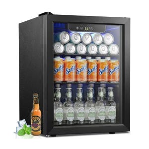 A compact mini fridge with a glass door displays several rows of canned Sunkist orange soda, generic silver cans, and bottles of Elderflower Tonic Water. A bottle of ginger beverage with ice cubes and mint leaves is placed beside the fridge.
