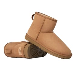 A pair of tan suede ankle boots with a shearling lining and rubber sole, branded with a logo tag on the heel.