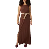 A woman wearing a sleeveless brown maxi dress with a side slit, accessorized with a beige knotted belt and maroon shoes.