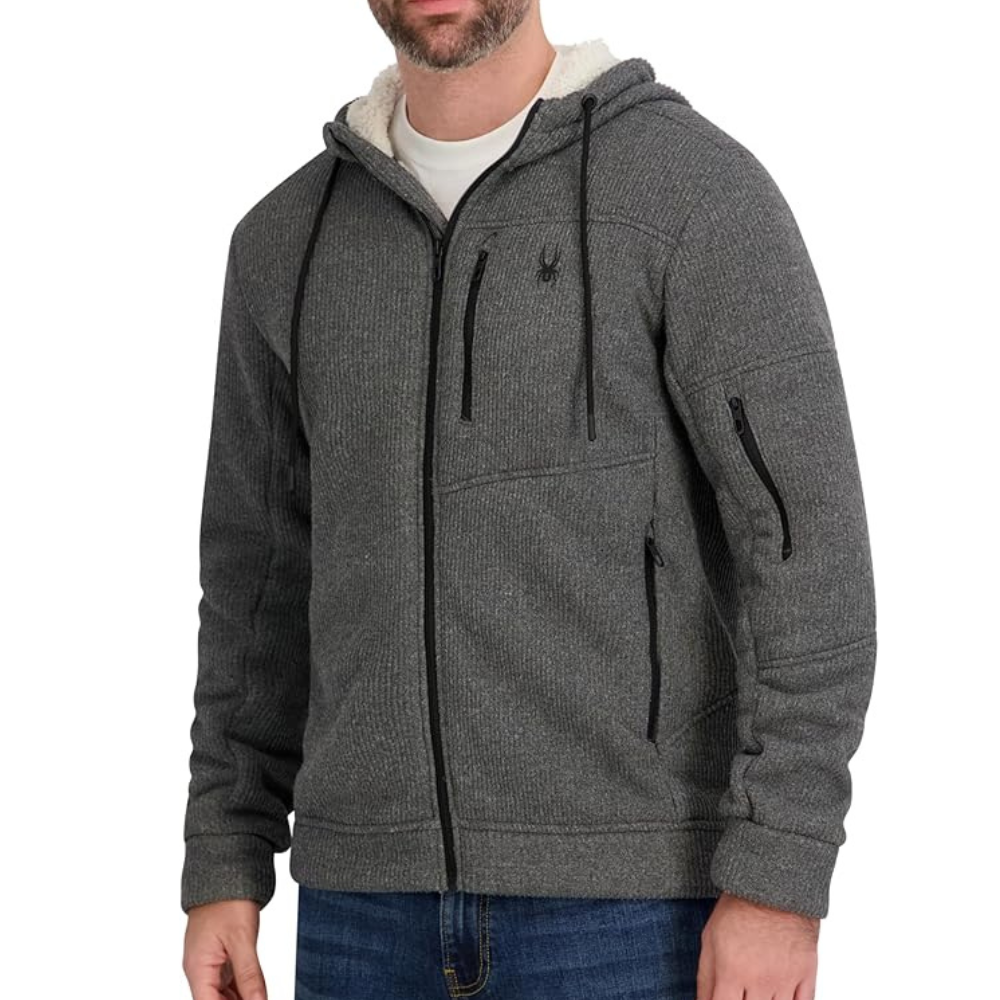 A gray zip-up hoodie with a textured fabric, featuring black drawstrings and various zippered pockets, worn over a white T-shirt and jeans.