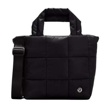 A black, quilted tote bag featuring a shoulder strap and top handles, with a small, circular logo on the front.