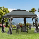 A gazebo with a gray canopy and mesh curtains is set up over a patio table and chairs on a grassy lawn, overlooking a scenic view of mountains and a lake.