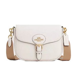 White Coach crossbody bag with gold hardware and a tan adjustable strap.