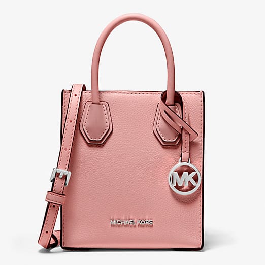 Pale pink leather handbag with a silver logo charm and a detachable shoulder strap.