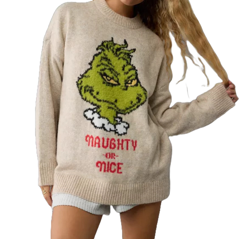 A beige sweater with an embroidered design of the Grinch's face above the phrase \“Naughty or Nice\“ in red, worn by a person with long blonde hair.