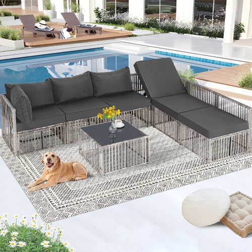 The 7pc Modular Patio Sectional Set features gray cushions on a metal frame, including a three-seat sofa, chaise lounge, and a square coffee table on a patterned outdoor rug, positioned beside a pool.