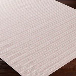 A beige and pink striped area rug on a dark wooden floor.