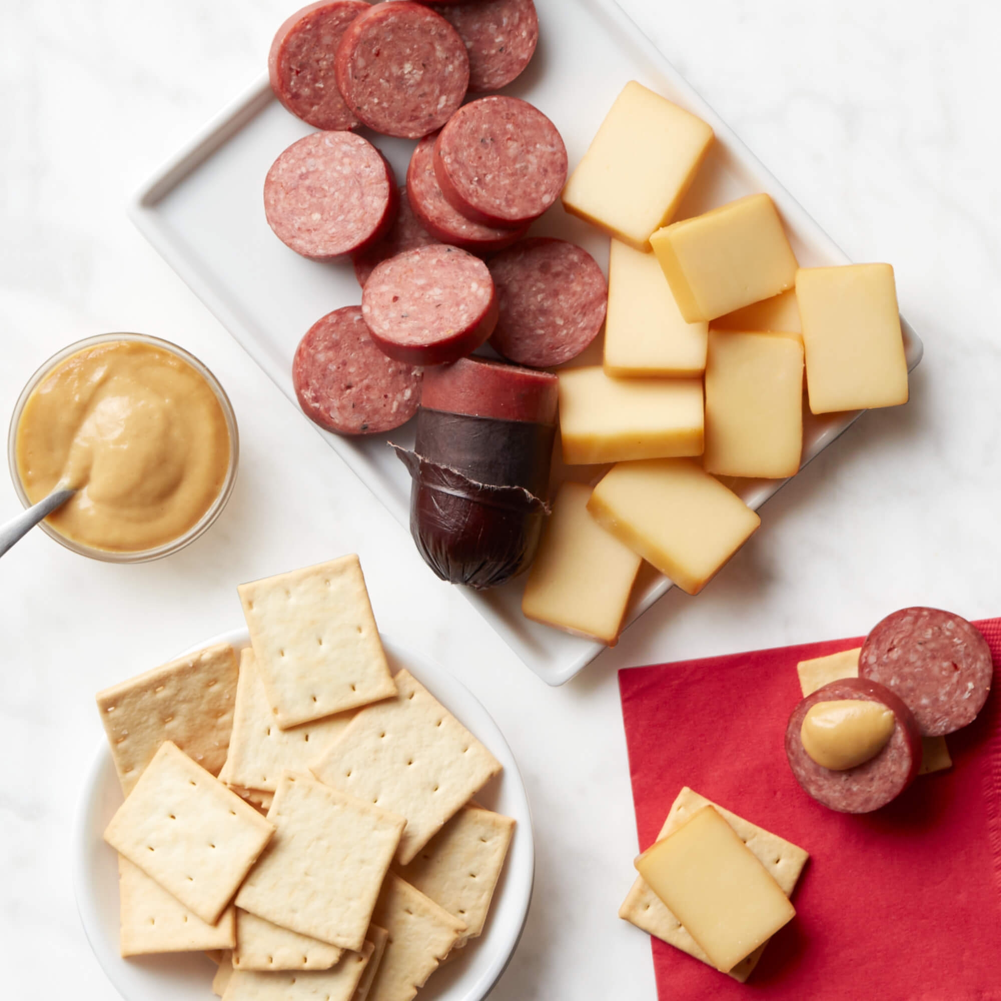 The Hickory Farms Signature Beef Sampler includes slices of signature beef sausage, cheese blocks, crackers, and a small jar of mustard.