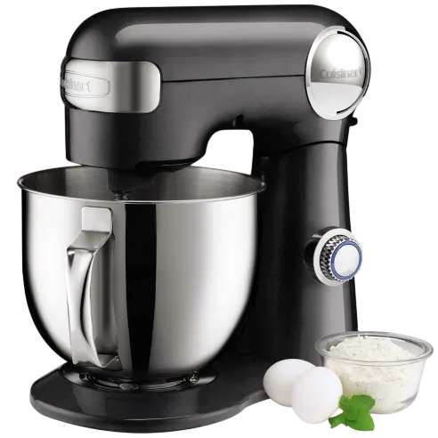 Black stand mixer with a metal mixing bowl, accompanied by two eggs, a small bowl of flour, and a mint garnish.