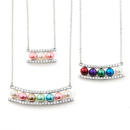 Three necklaces featuring colorful pearl-like beads, each set between two curved bars adorned with small clear gemstones.
