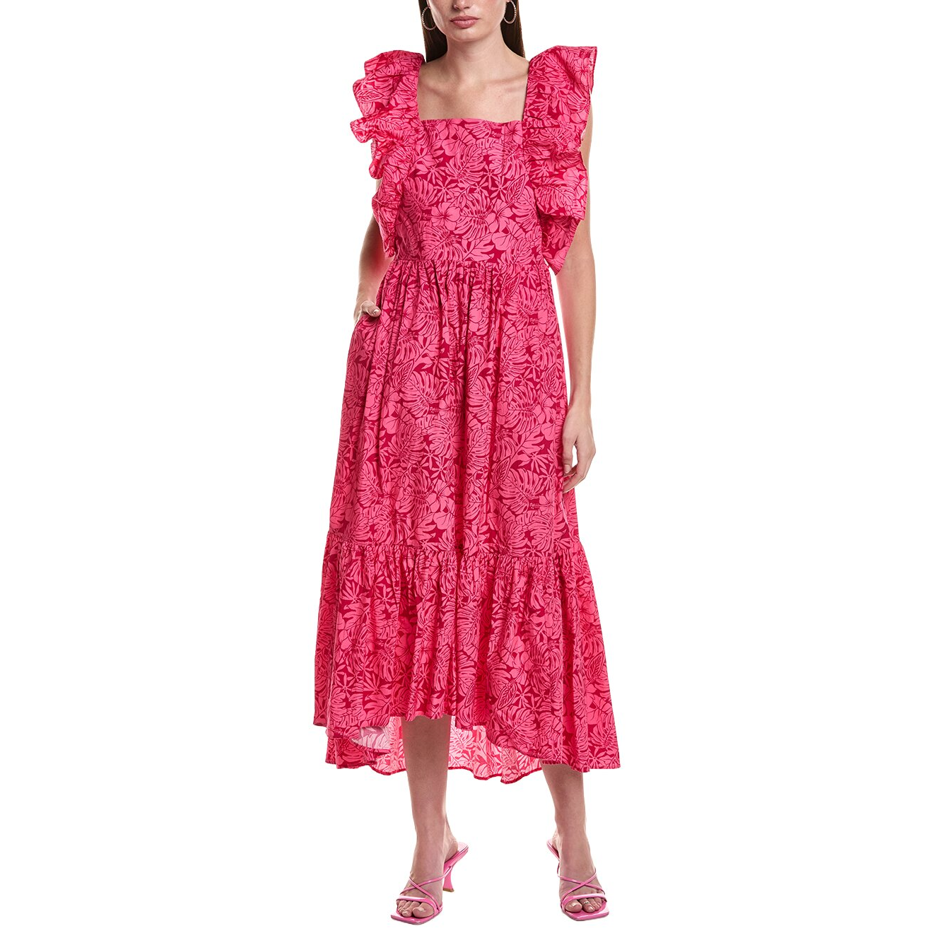 A woman wearing a pink, maxi-length dress with floral patterns, ruffled sleeves, and square neckline. She pairs the dress with pink heeled sandals.