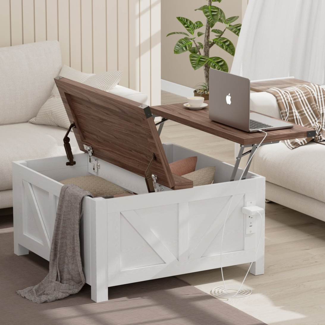 White wooden storage trunk with a lift-top table, revealing interior storage space, holding pillows and a blanket. A laptop and cup rest on the extended tabletop. A power outlet is mounted on the side.