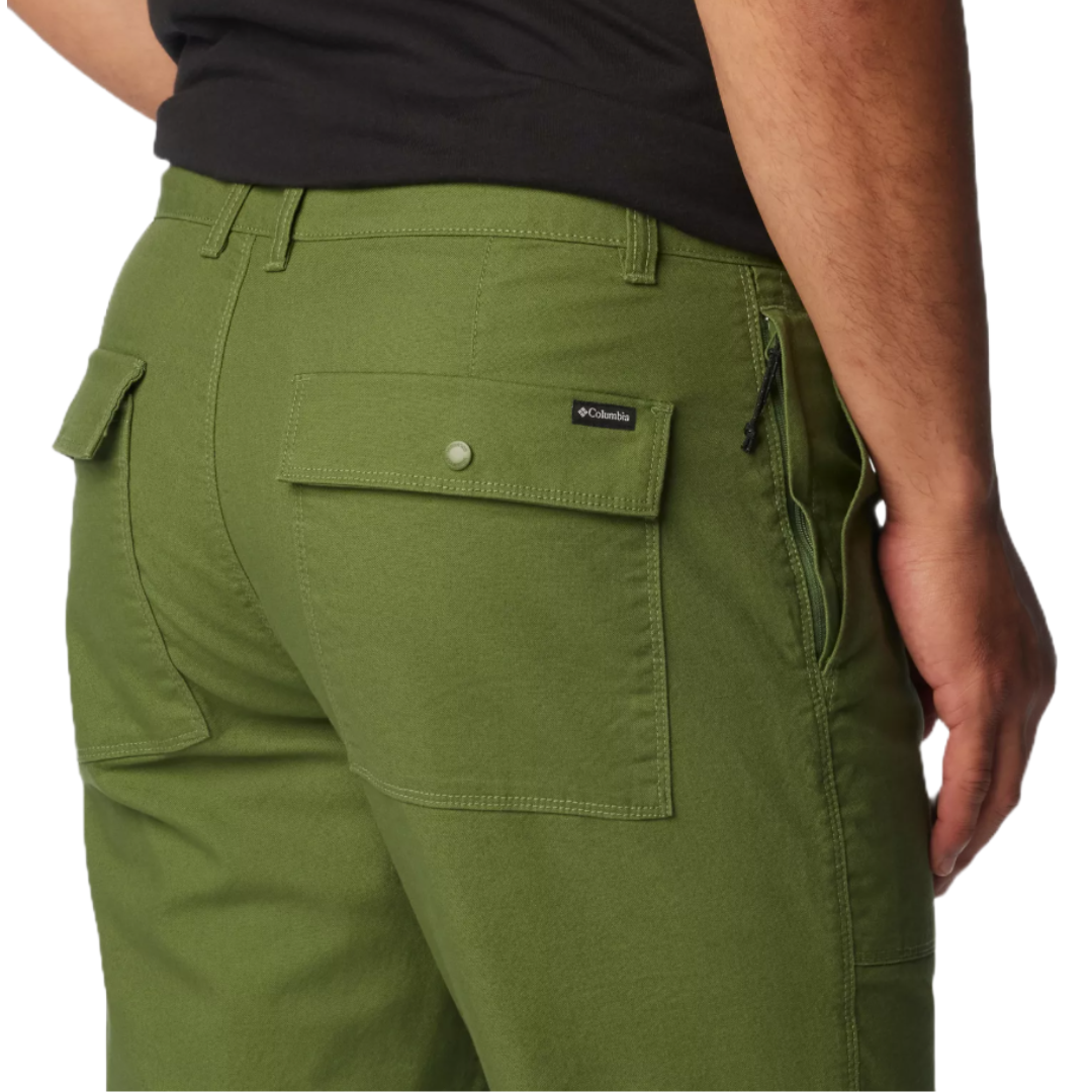 A person wearing green Columbia pants, featuring a back pocket with a button flap and a small logo tag.