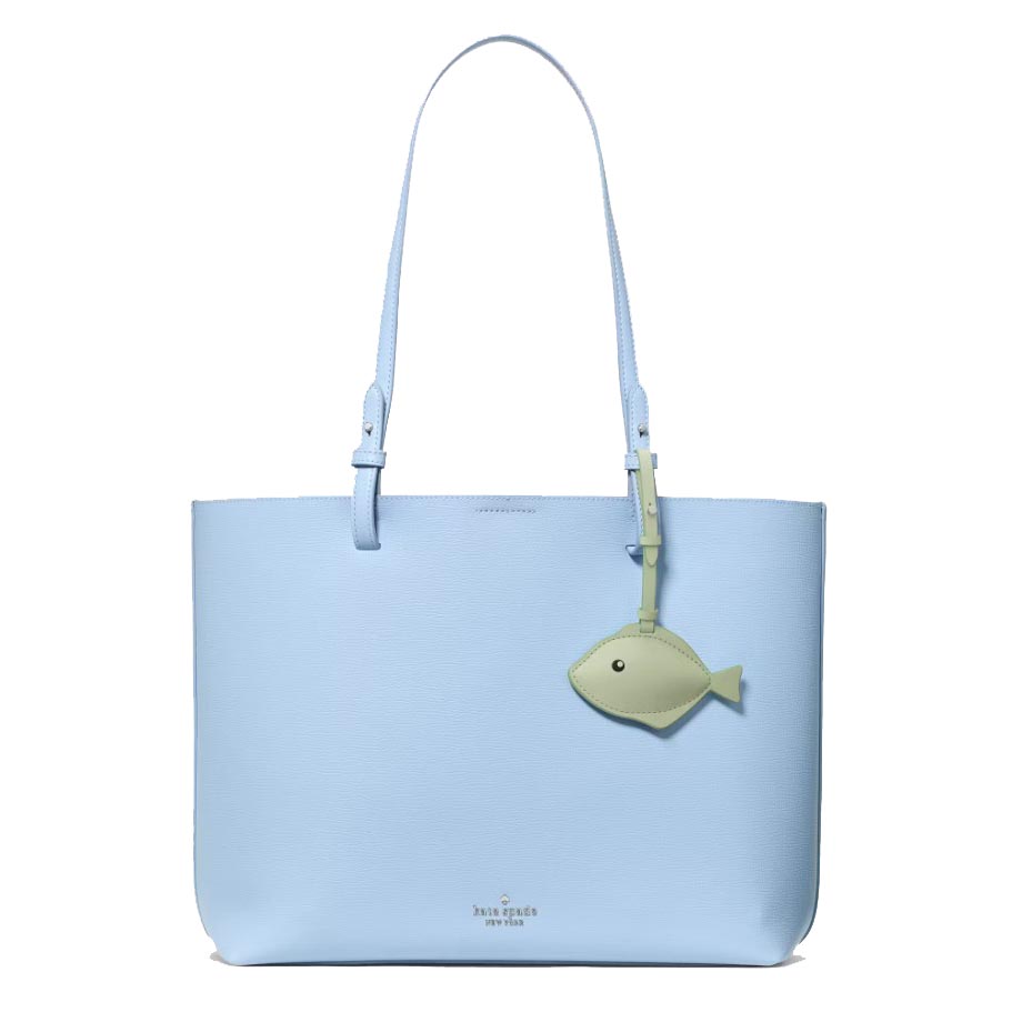 A light blue tote bag with a long strap and a small green fish-shaped charm.