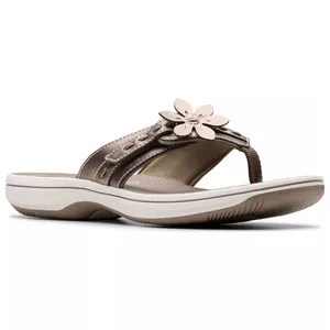 A brown sandal with a flower decoration on the strap, featuring a cushioned sole and white trim.