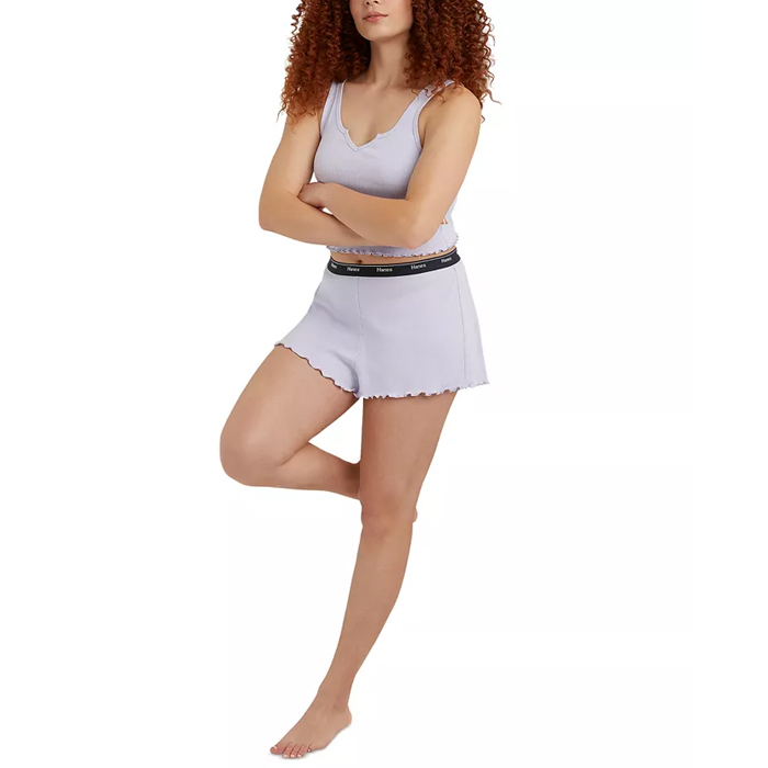 A woman stands with arms crossed wearing a light gray scalloped-hem shorts and a matching tank top.