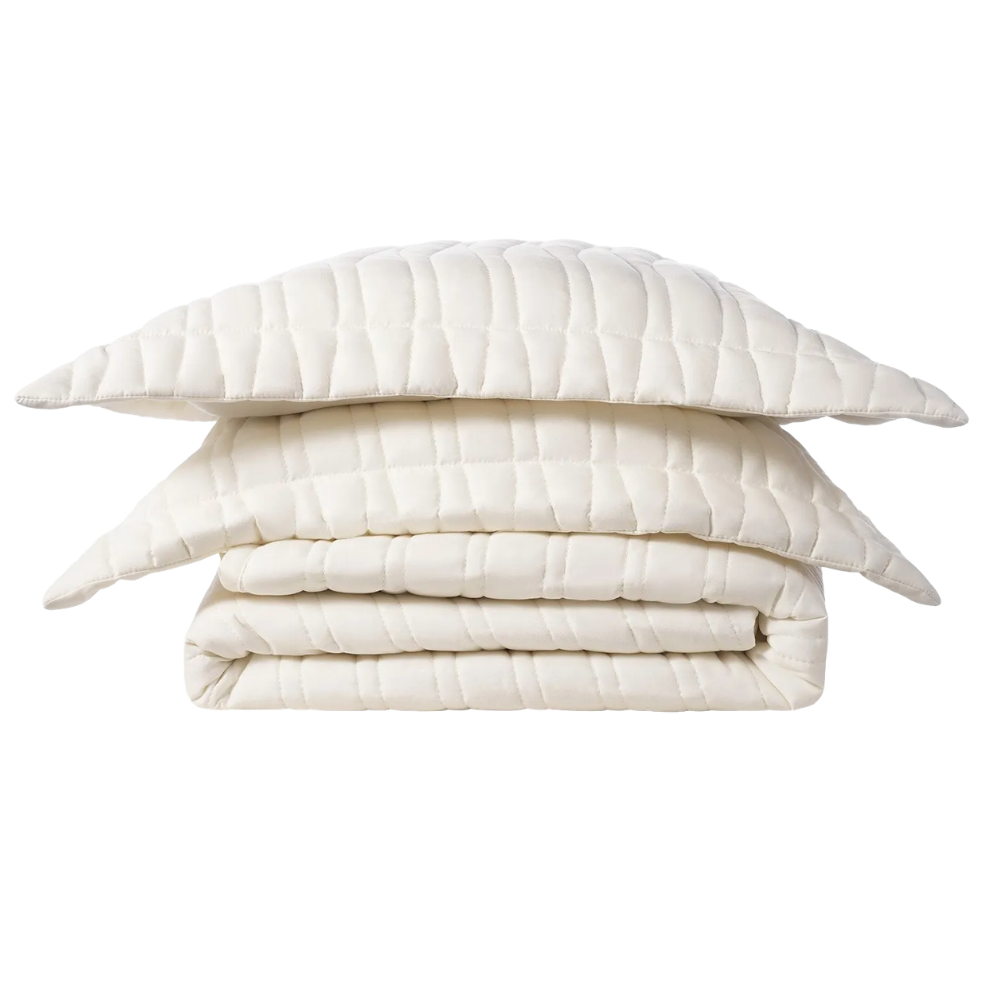 A folded, quilted, cream-colored bedding set comprising a comforter and two matching pillowcases with a grid pattern.