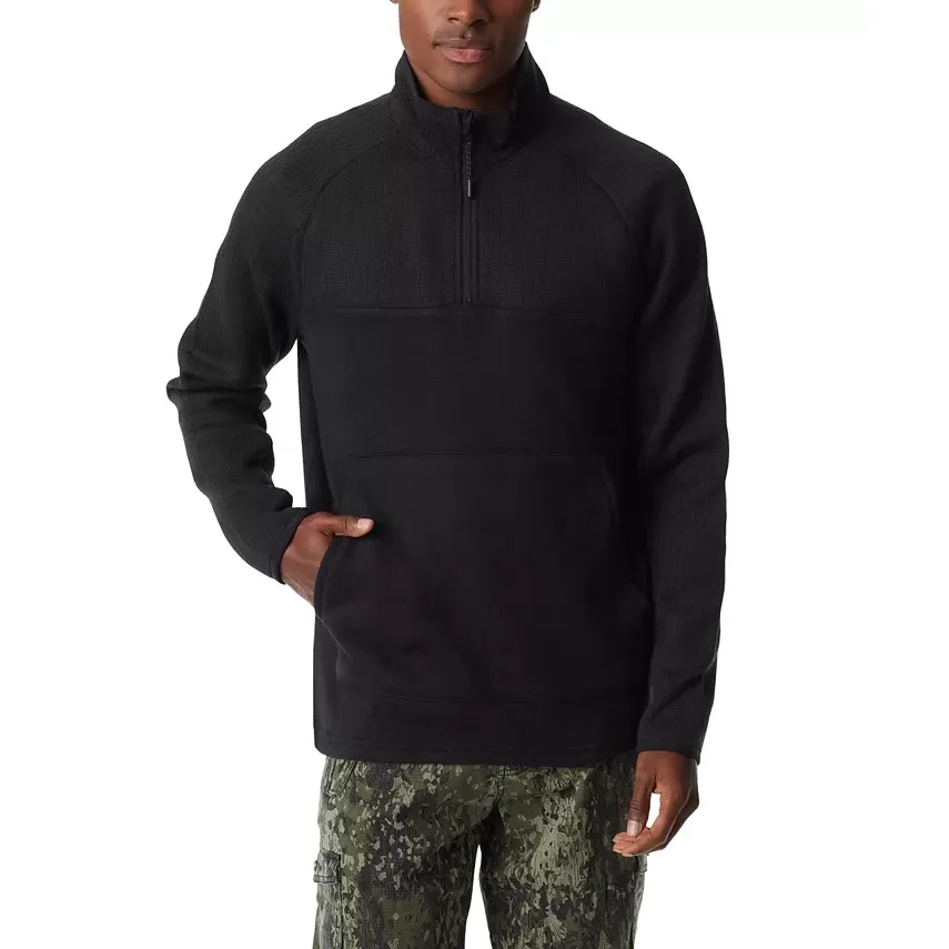 A man wearing a black half-zip pullover with a front kangaroo pocket and camo pants.