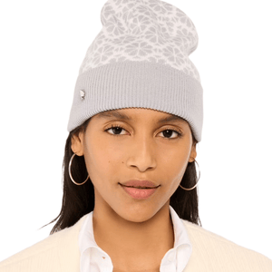 A woman wearing a light gray knit beanie with a white patterned top, paired with large hoop earrings and a white shirt with a blazer.