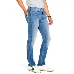 Light blue stretch-fit jeans with a slim, tapered leg design, worn with a casual grey t-shirt. The denim has a slightly faded look, with classic five-pocket styling and stitching details. Paired with white sneakers featuring green star accents.