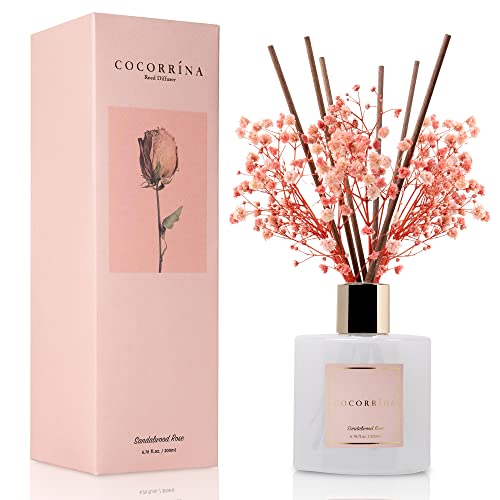 Cocorrína reed diffuser in a Sandalwood Rose scent, featuring a bottle with decorative reeds and small pink flowers, alongside its matching pink packaging.