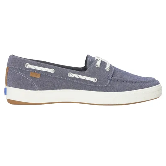 A casual, navy canvas boat shoe with white laces, eyelets, and a white rubber sole featuring a subtle brown accent on the heel.