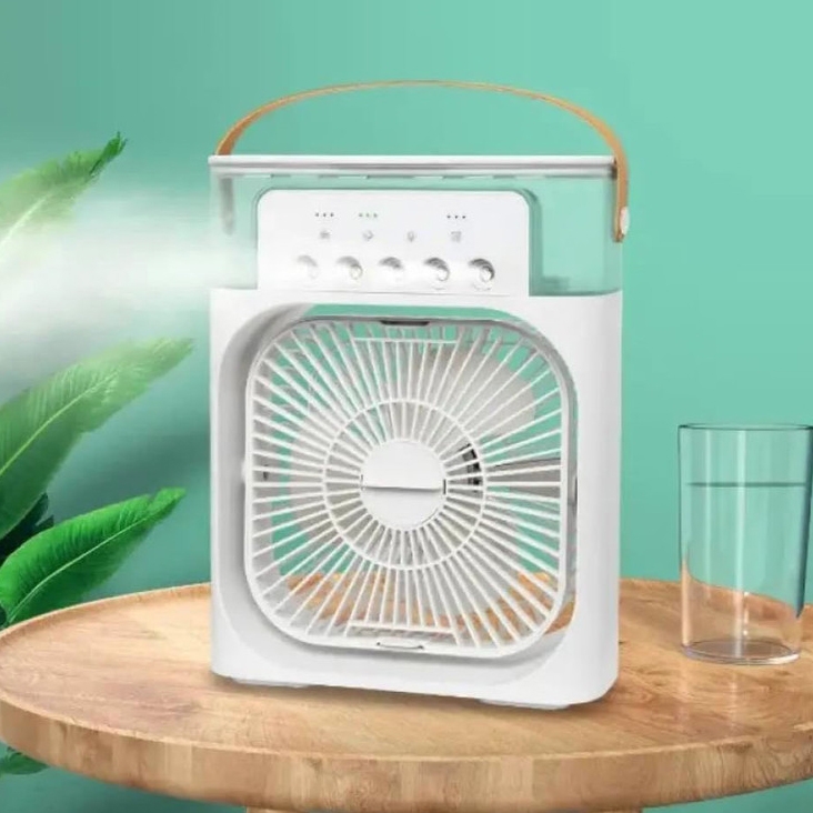 A square fan with a built-in humidifier is displayed, featuring a handle for portability, control buttons, and located on a wooden surface nearby a glass.