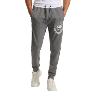 Gray sweatpants with a white drawstring, featuring a graphic logo on one leg. Paired with white sneakers.