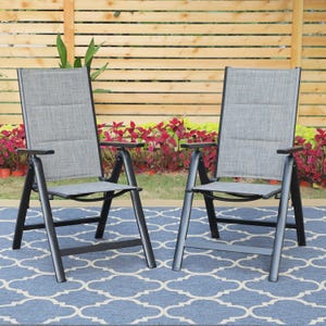 Two outdoor patio chairs with gray fabric seats and backs framed by black metal, set on a blue patterned outdoor rug, with a wooden fence and plants in the background.