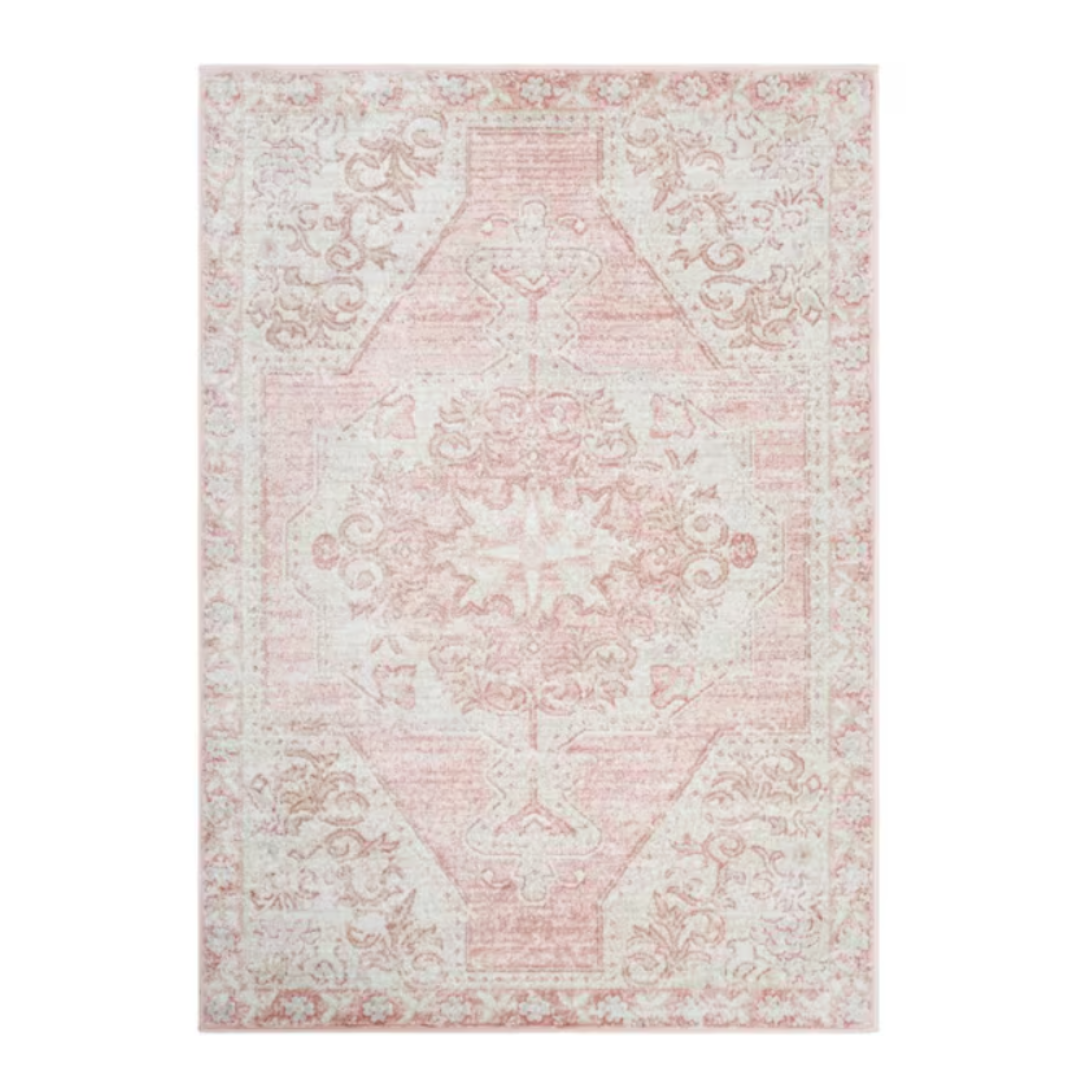 A light pink and cream area rug featuring an intricate floral and geometric pattern, giving it a vintage aesthetic.