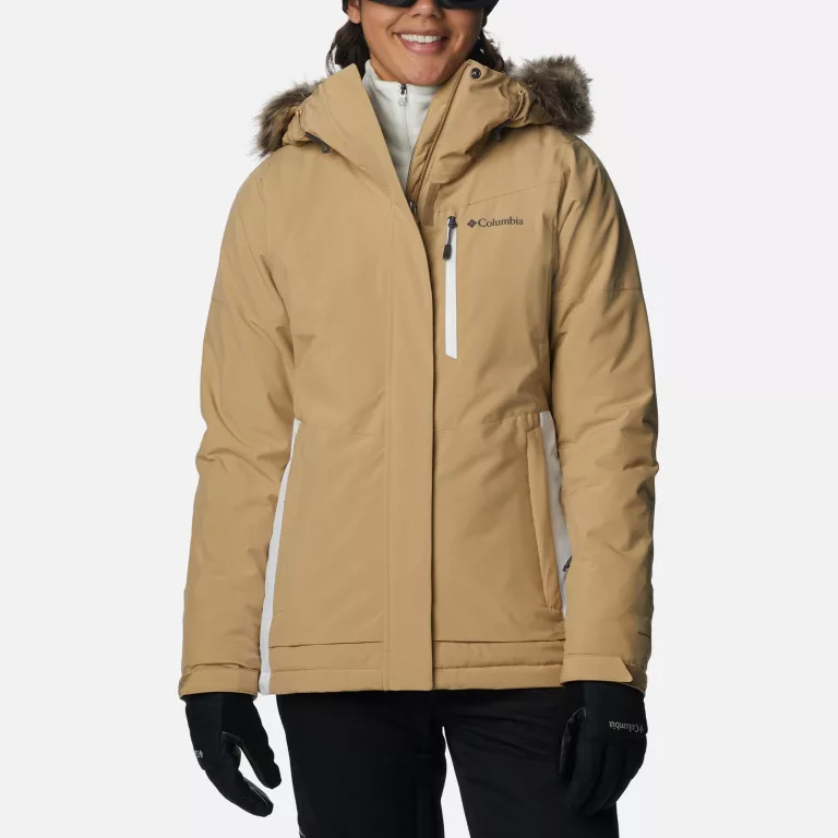 A woman wearing a beige Columbia winter jacket with fur-lined hood and black gloves.