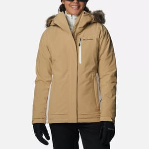 A woman wearing a beige Columbia winter jacket with fur-lined hood and black gloves.
