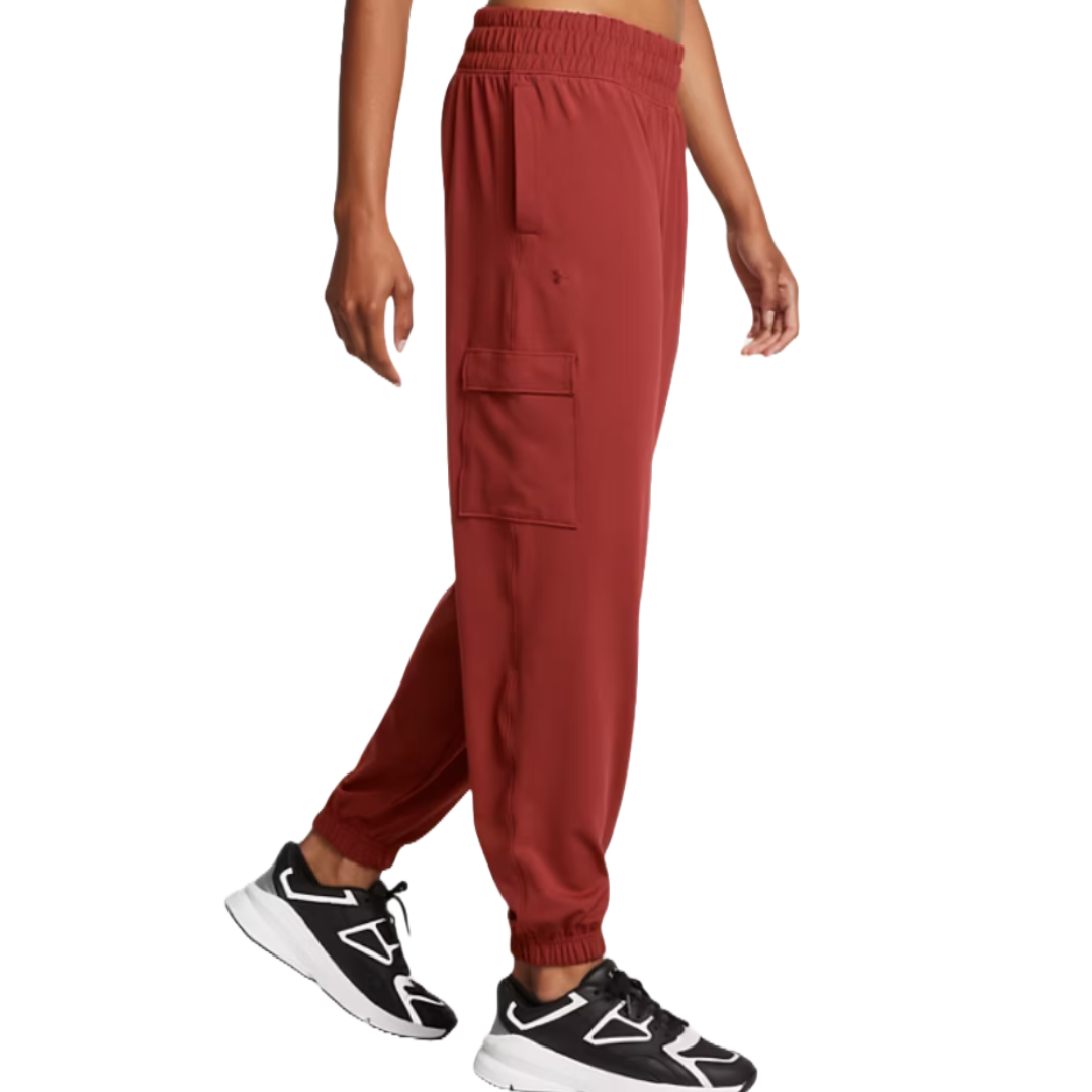 UA Meridian Cargo Joggers in red feature an elastic waistband, side cargo pockets, and elastic cuffs, paired with black and white athletic shoes.