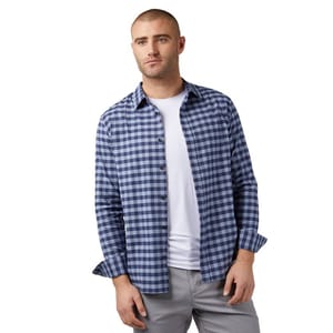 A man is wearing a blue and white checkered button-up shirt over a white T-shirt, paired with gray pants.